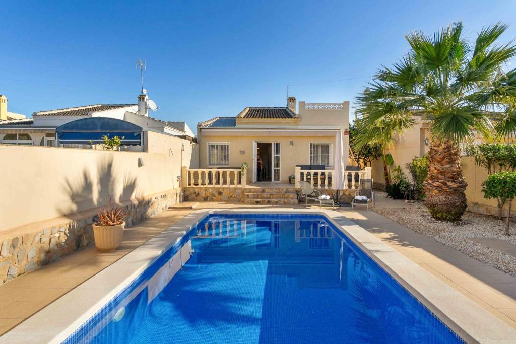 a swimming pool in front of a house at Beautiful and cozy Villa with private pool in urb, San Luis, El Chaparral, Torre in Torrevieja