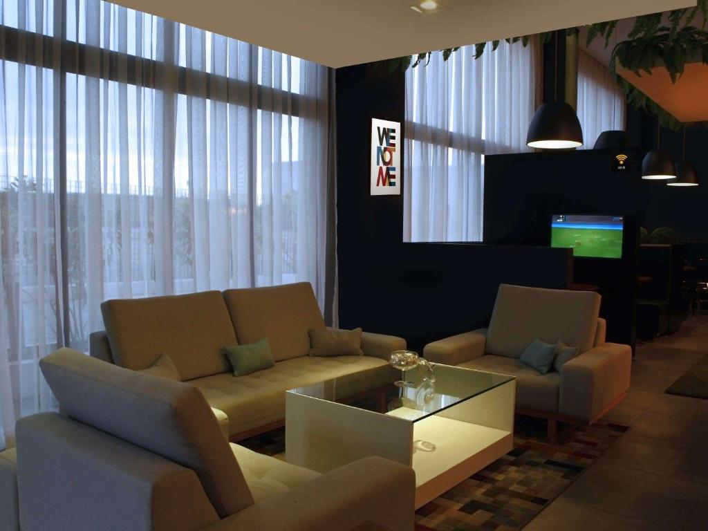 sala de estar con sofá, sillas y TV en ibis Styles Palmas en Palmas