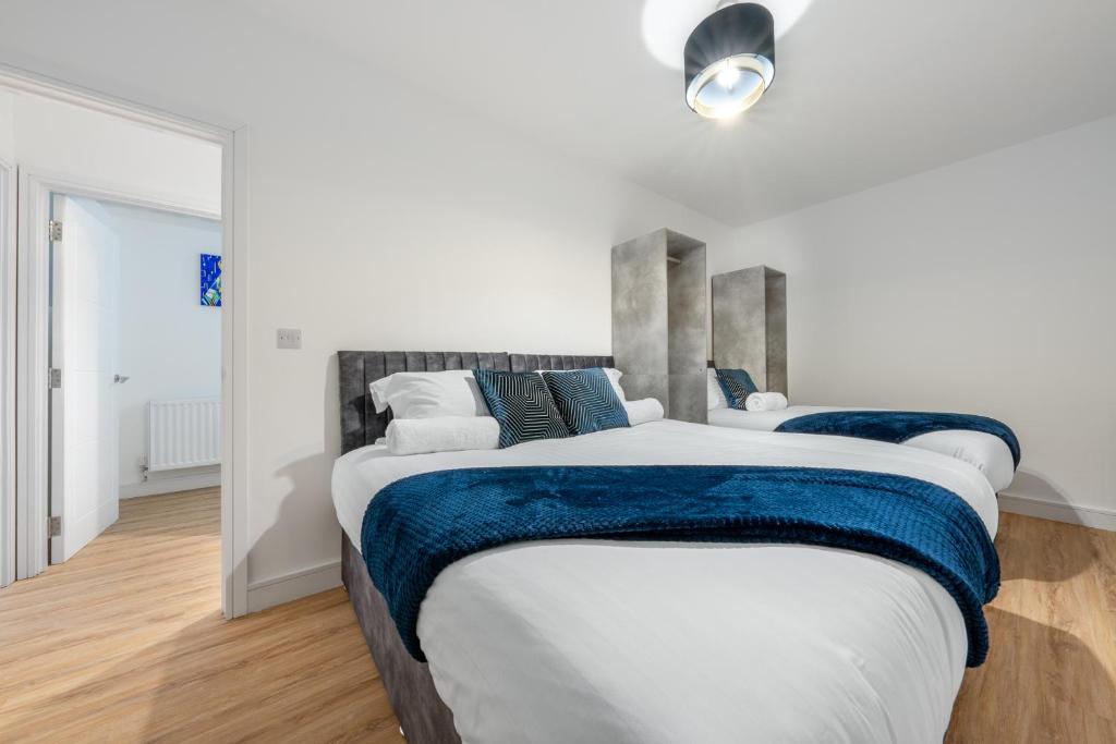 a bedroom with two large beds with blue blankets at Modern Stylish 2 bedroom apartment in the heart of Potters Bar in Potters Bar