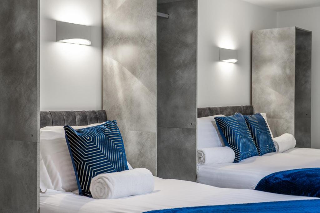 1 dormitorio con 2 camas y almohadas azules y blancas en Modern Stylish 2 bedroom apartment in the heart of Potters Bar en Potters Bar