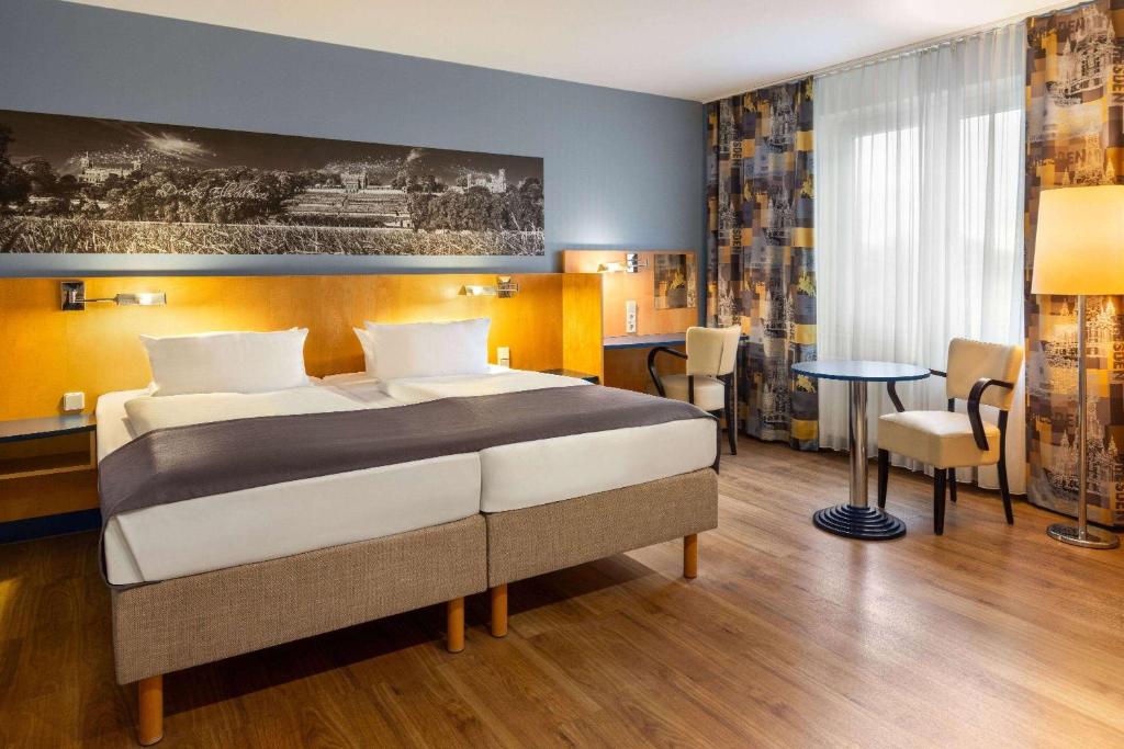 a hotel room with a bed and a table and chairs at Amedia Dresden Elbpromenade, Trademark Collection by Wyndham in Dresden