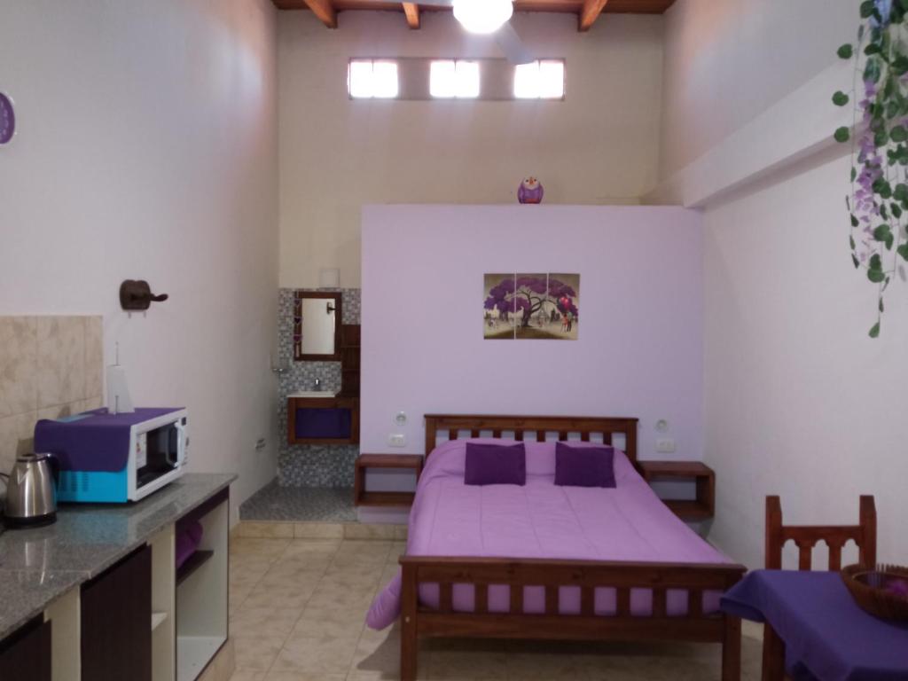 Un dormitorio con una cama con sábanas moradas y un microondas. en Violeta Monoambiente, en Salta