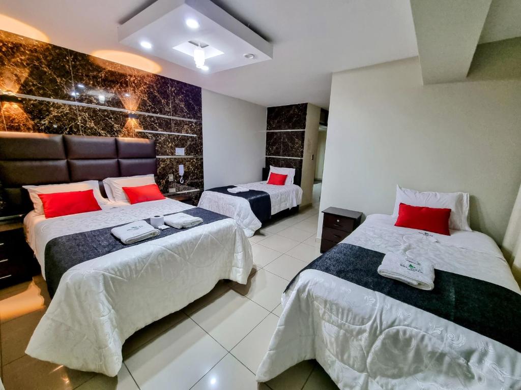Habitación con 2 camas y almohadas rojas. en Hotel del Valle, en Huancayo
