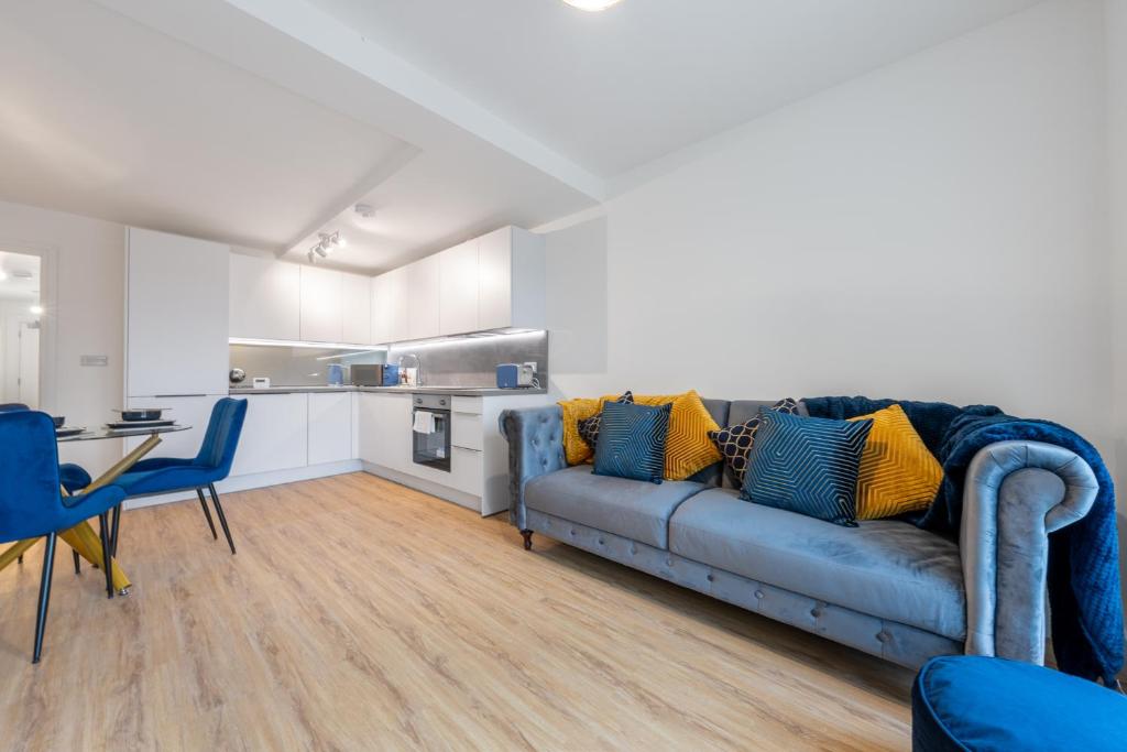 a living room with a blue couch and a kitchen at Modern Stylish 1 bedroom apartment in the heart of Potters Bar in Potters Bar