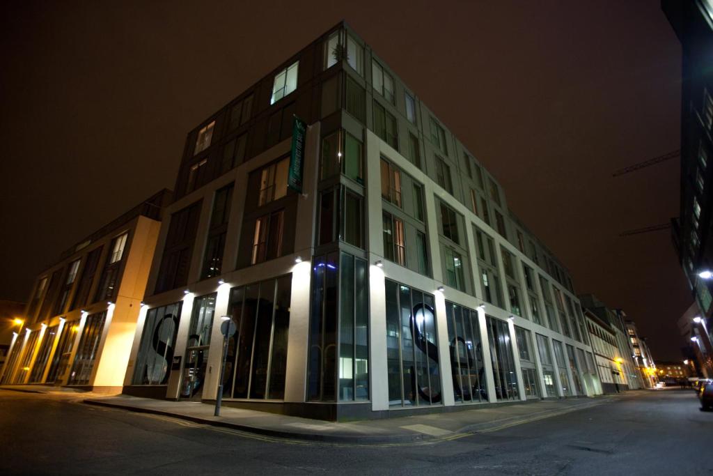 The Spires Serviced Apartments Birmingham في برمنغهام: مبنى كبير مع نوافذ زجاجية في الليل