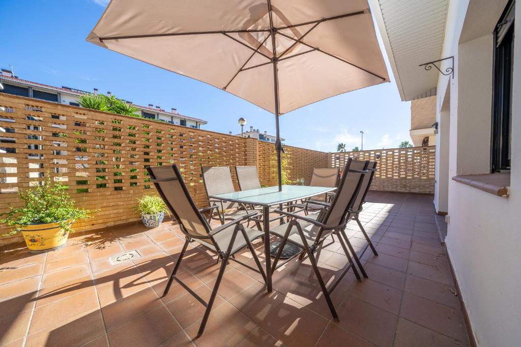 een patio met een tafel en stoelen en een parasol bij HomeHolidaysRentals Fortuny - Costa Barcelona in Pineda de Mar