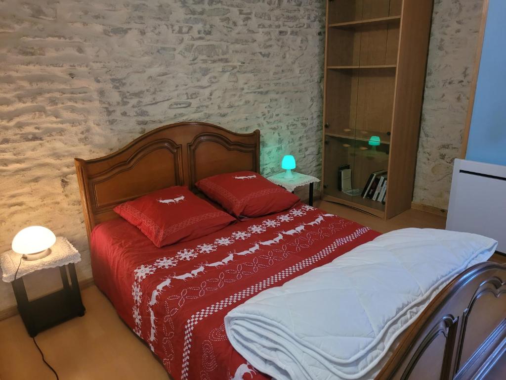 Schlafzimmer mit einem Bett mit einer roten Bettdecke in der Unterkunft Le chalet in Vertamboz