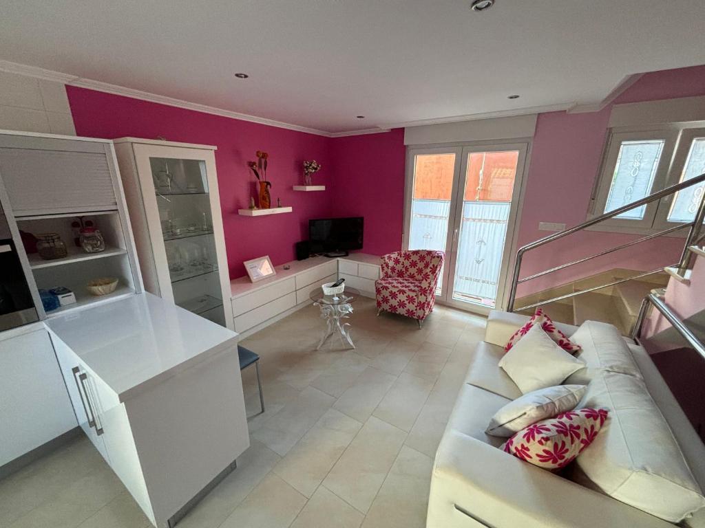 sala de estar con sofá blanco y paredes rosas en Casa Lalo, en Camariñas
