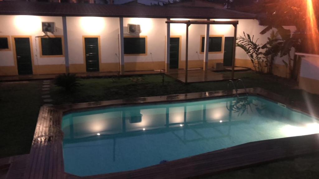 a swimming pool in front of a house at night at Baía Villa in São Tomé