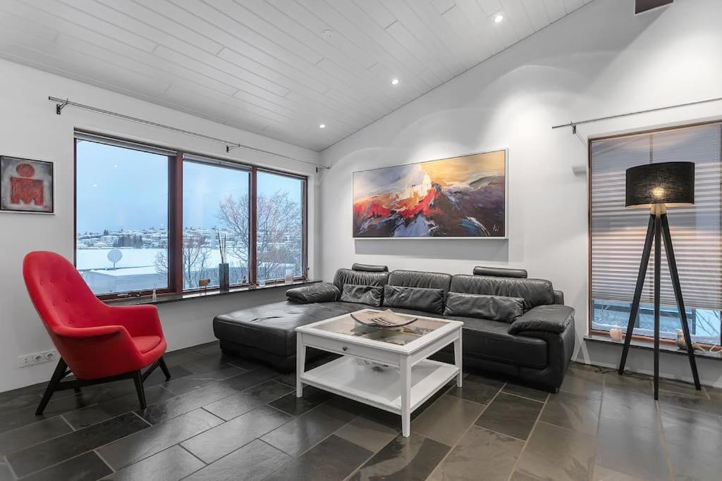 Modern 3BR Oasis in Kópavogur في ريكيافيك: غرفة معيشة مع أريكة وكرسي احمر