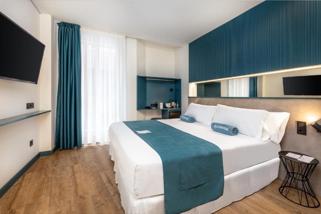 um quarto com uma grande cama branca e um cobertor azul em Occidental Las Canteras em Las Palmas de Gran Canaria