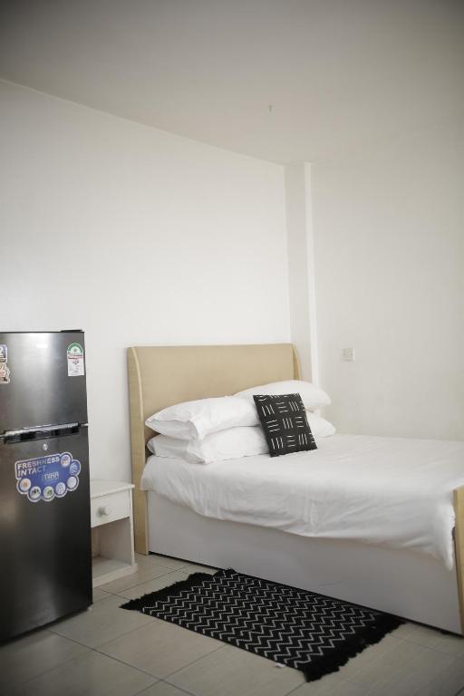 una camera da letto con frigorifero nero accanto a un letto di Eagle Nest furnished studio apartments at Eagle Tower. a Nairobi