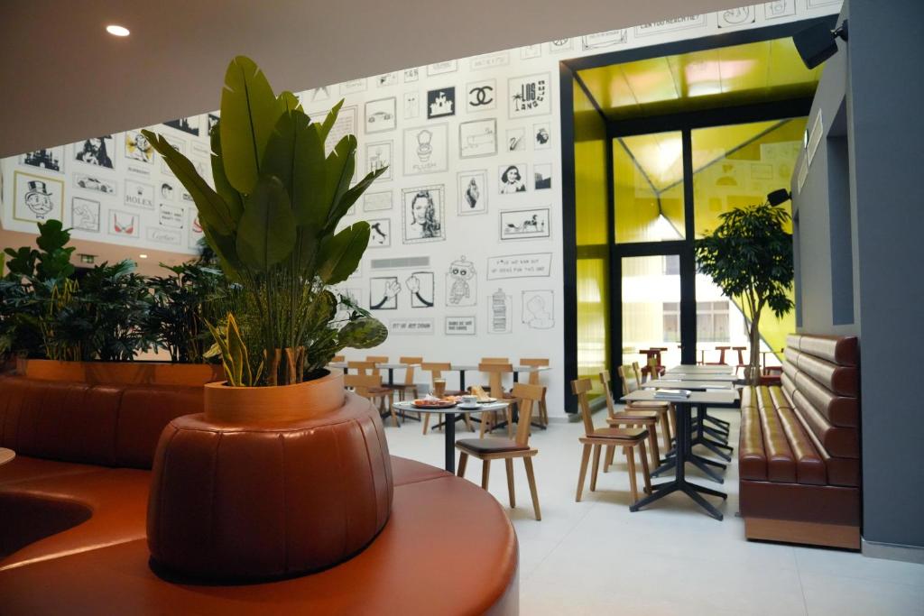 a room with tables and chairs and a potted plant at SO City Hotel Adults Only in St. Julianʼs