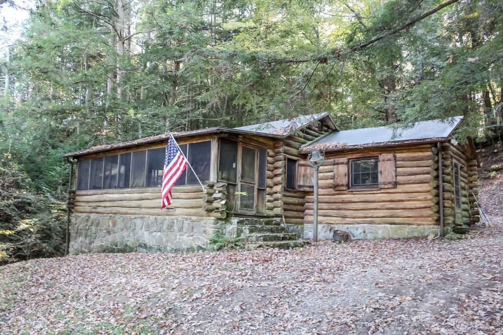 una cabaña de madera con una bandera americana delante de ella en Russell Cabin, en Logan