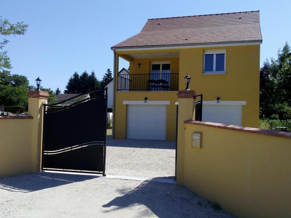uma casa com um portão preto e uma garagem em GITE DE L'OISILLIERE em Huisseau-sur-Cosson