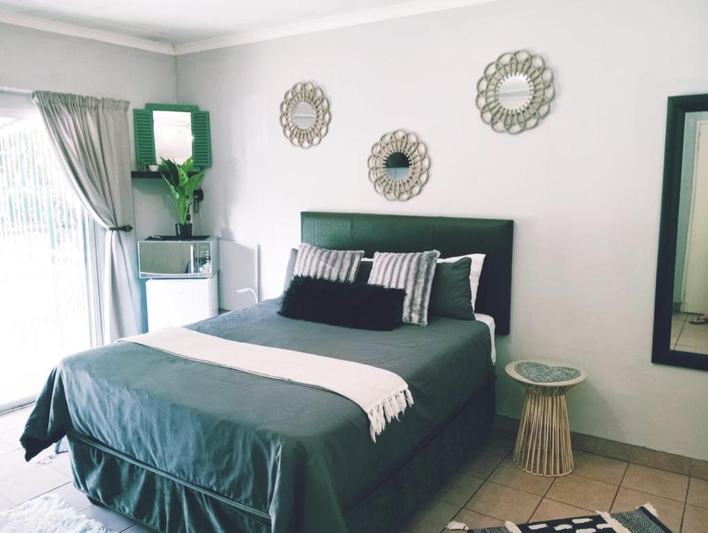 a bedroom with a bed with a green comforter at Be Our Guest Near OR TAMBO International Airport Room 2 in Boksburg