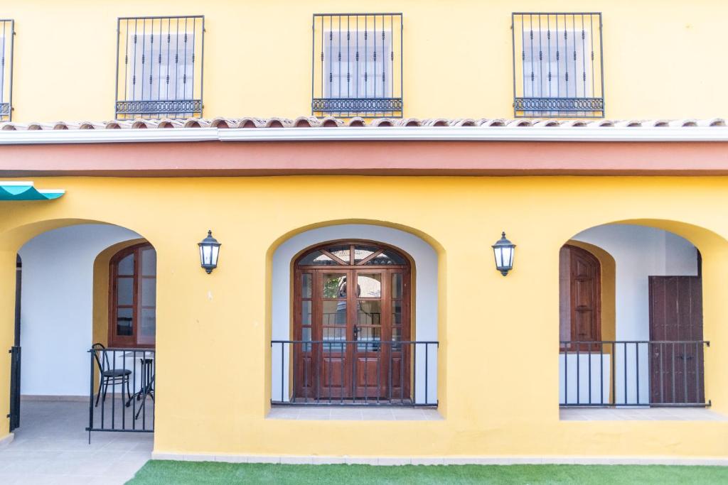 een geel huis met 2 deuren en een balkon bij Casa Rural "compartida" La Loma in Granada