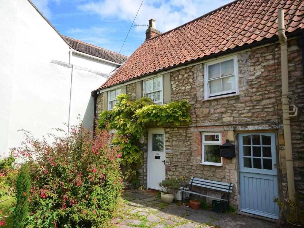 une maison en pierre avec un banc devant elle dans l'établissement 2 bed in Wells 52STT, à Wells