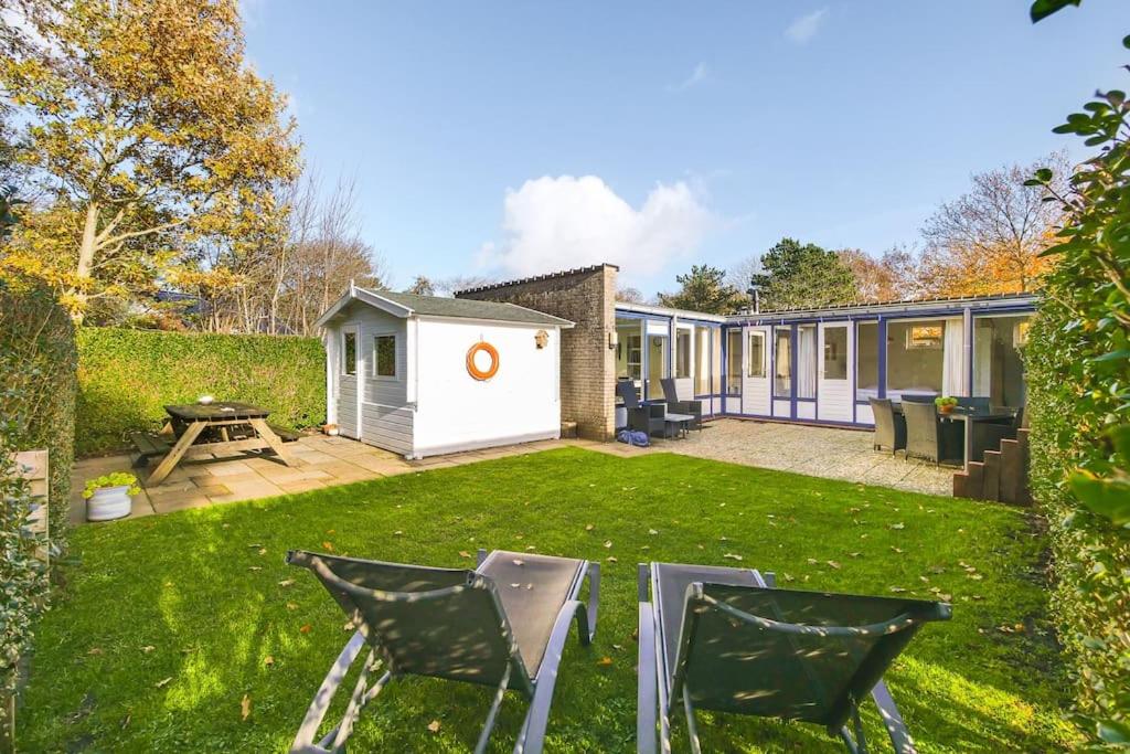 a backyard with two chairs and a house at Duinland 251 - Park Duinland Sint Maartenszee in Sint Maartensvlotbrug