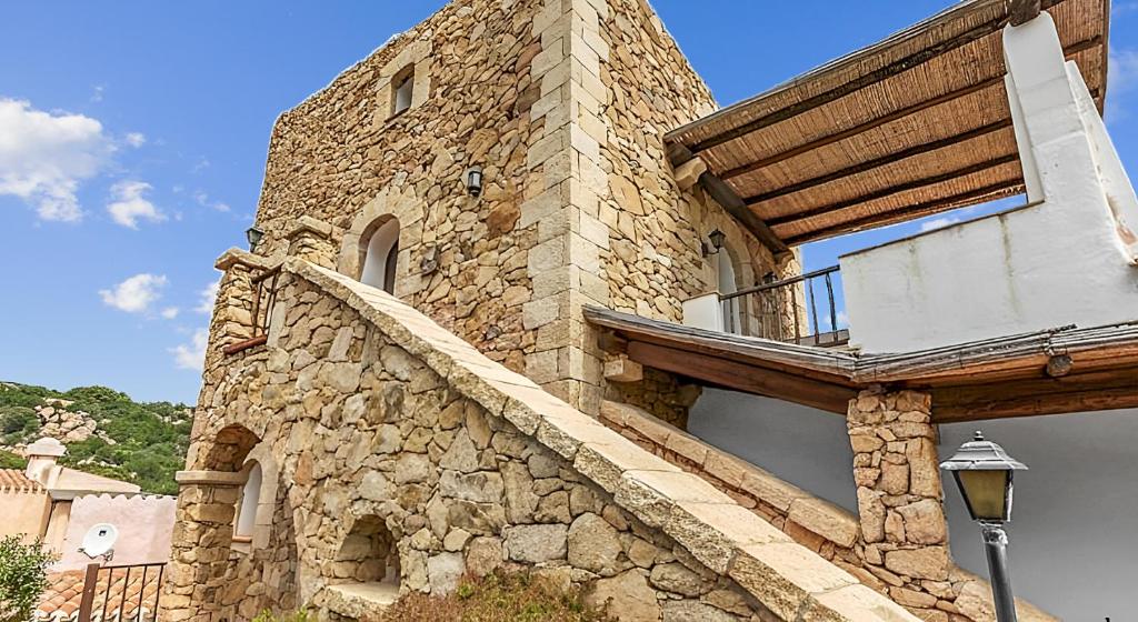 un edificio de piedra con un balcón en un lateral. en -LUXURY- Torretta con Piscina e Spiaggia a 300 MT, en Liscia di Vacca