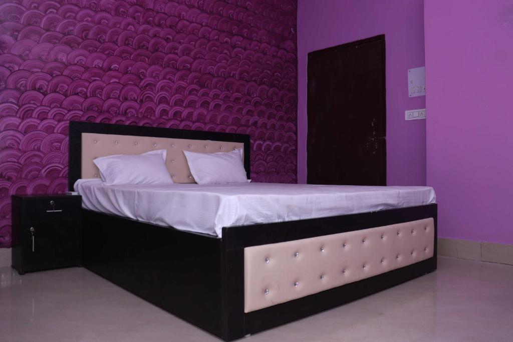 a bedroom with a bed with a purple wall at SPOT ON Gajadhar Rest House in Deoghar