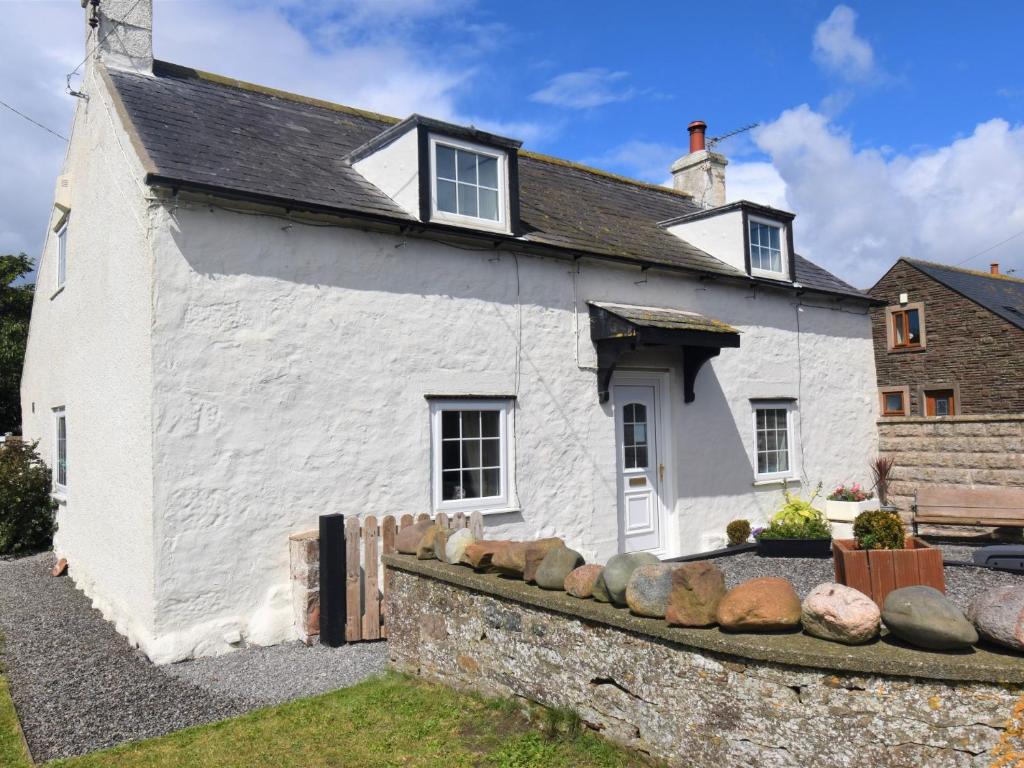 a white house with rocks in front of it at 2 bed property in Mawbray Cumbria SZ214 in Mawbray