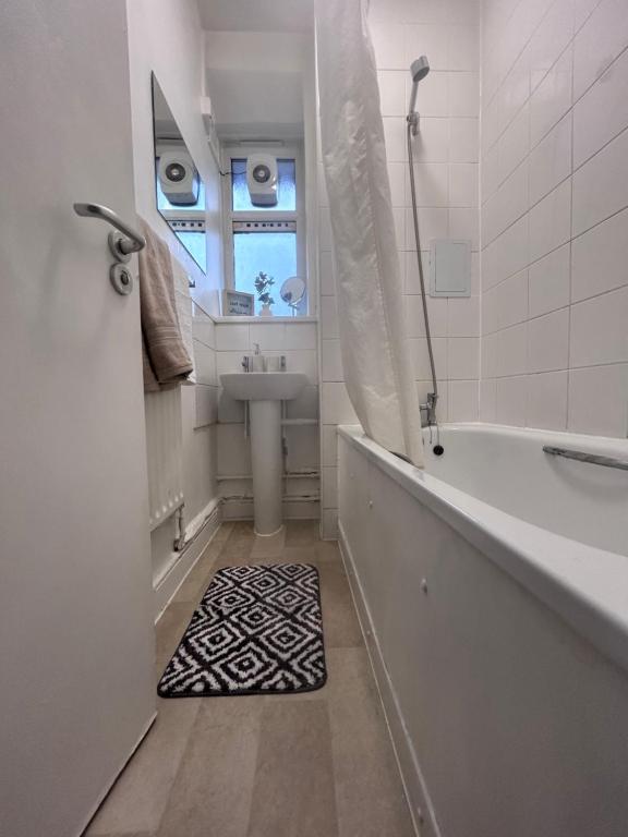 a bathroom with a tub and a sink and a window at Quirky Hackney Wick 1 bed Flat! in London