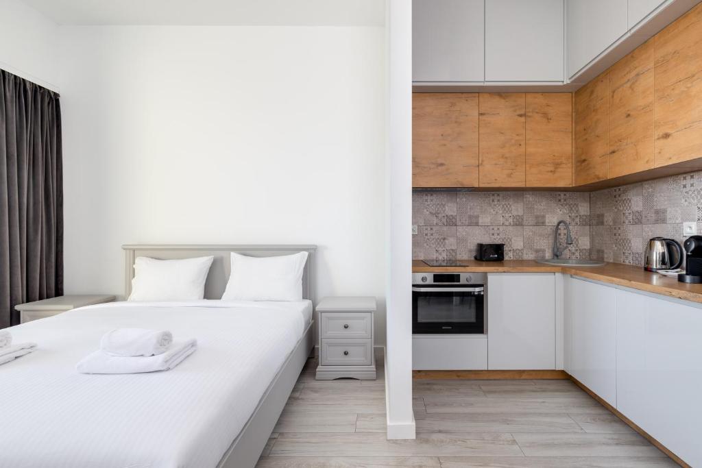 a bedroom with a white bed and a kitchen at Hanza Tower Studio 738 in Szczecin