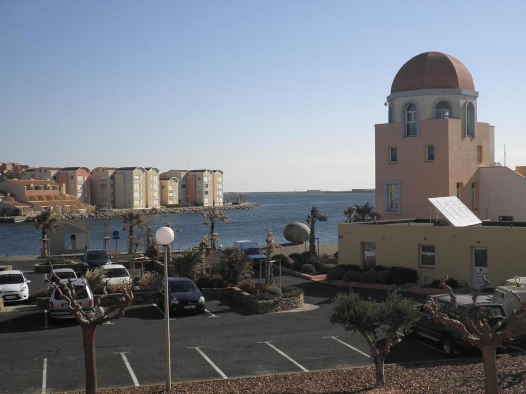 a view of a parking lot with a building and the ocean at Appartement Gruissan, 1 pièce, 6 personnes - FR-1-229-65 in Gruissan