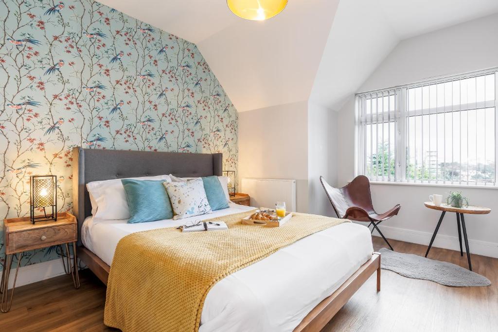 a bedroom with a bed and a wall with floral wallpaper at Sea Breeze Apartments in Bournemouth