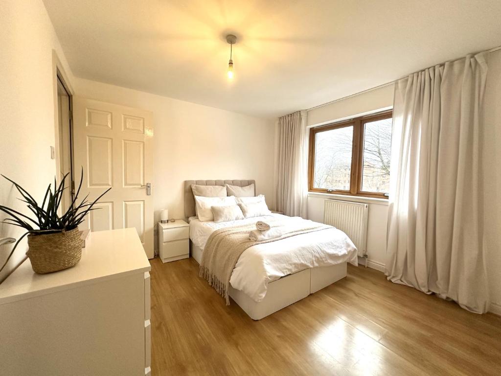 a white bedroom with a bed and a window at Private room with en-suite and parking in shared flat in Glasgow