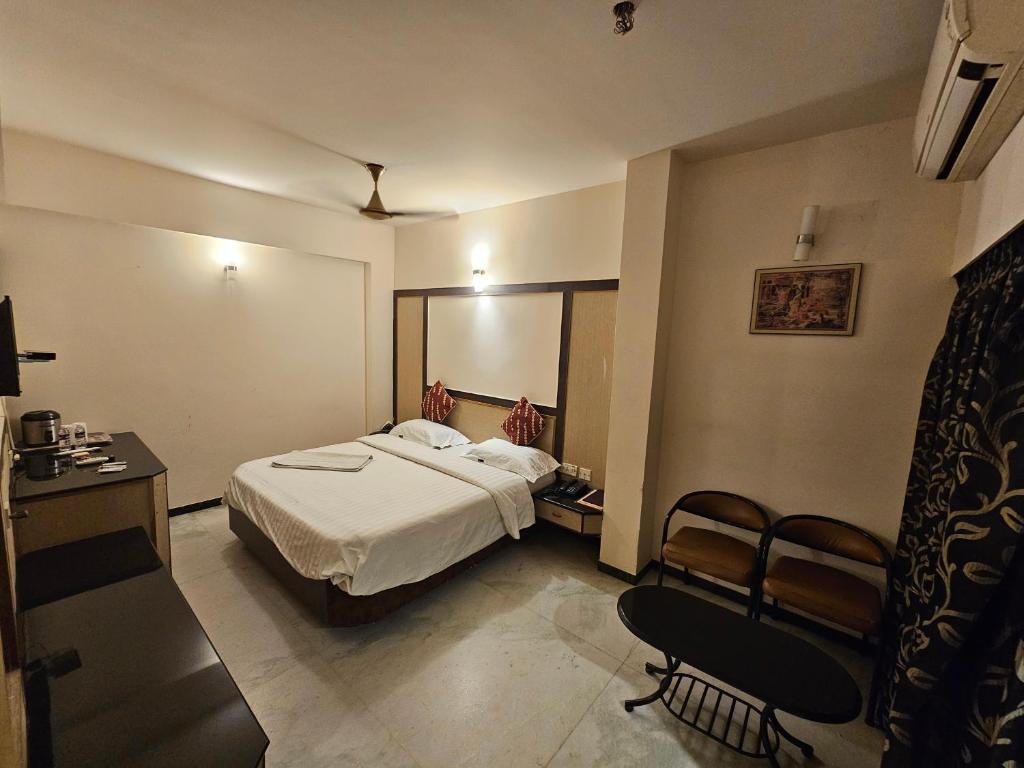 a hotel room with a bed and a table and chairs at HOTEL MERILIN in Erode