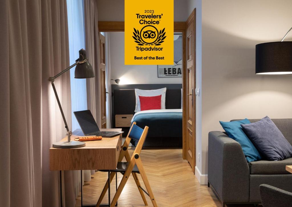 a room with a bed and a desk with a laptop at STRADONIA Serviced Apartments in Kraków
