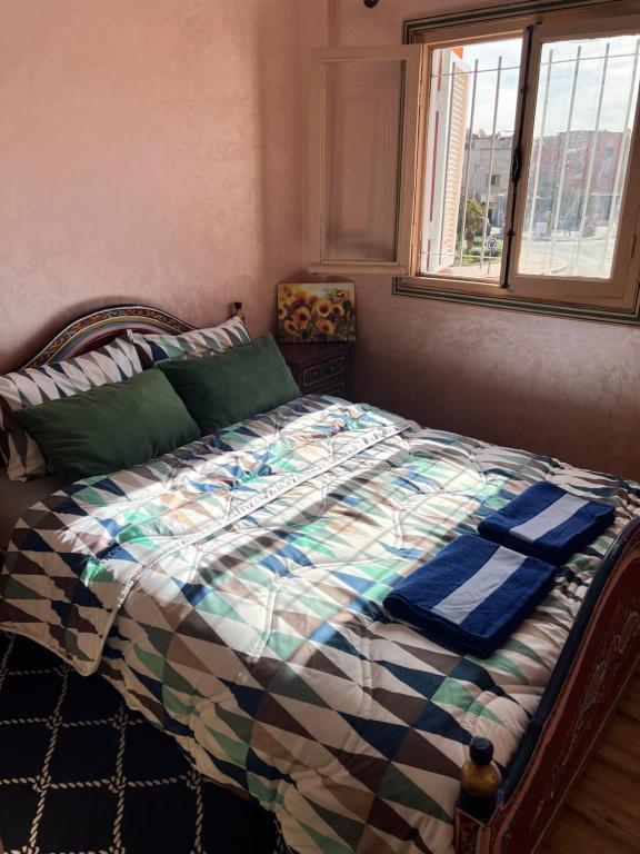 a bedroom with a bed with a comforter and a window at Julie's AIRPORT Apartment in Marrakech