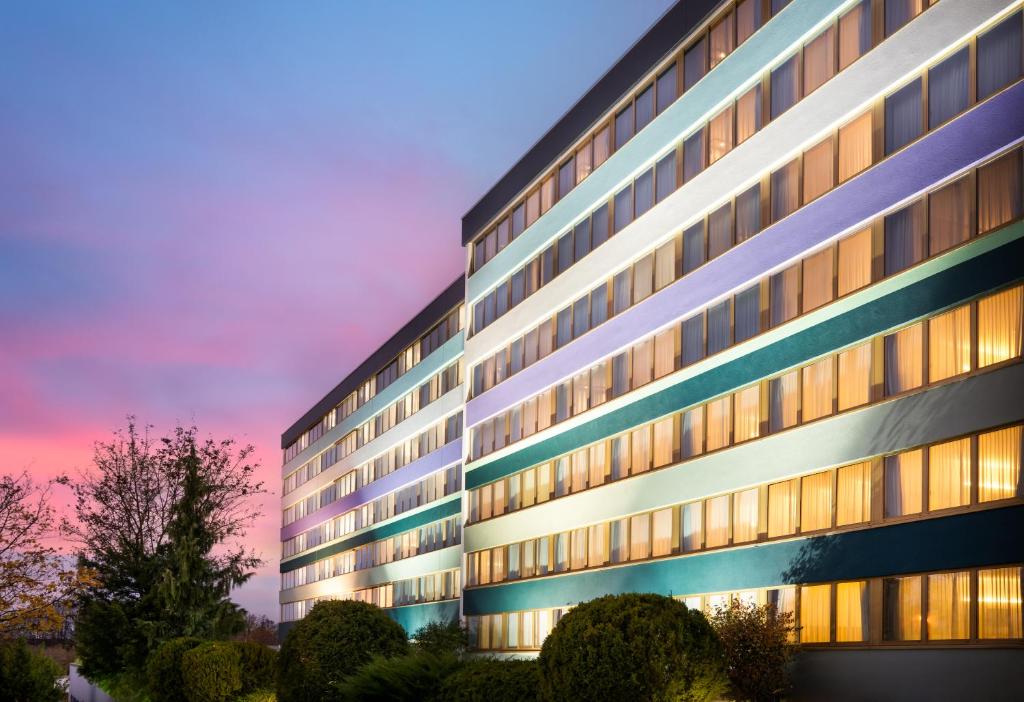 a tall building with a sunset in the background at Abacco by Rilano in Korntal-Münchingen