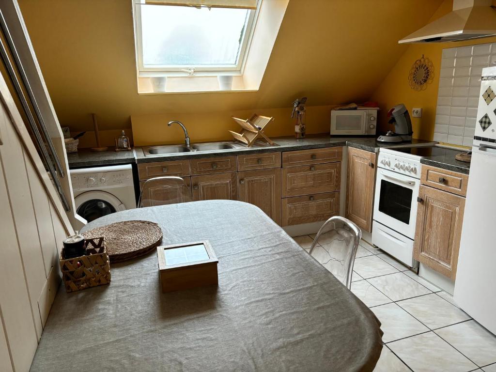 una cucina con tavolo, lavandino e piano cottura di LES FLORALIES a Froberville