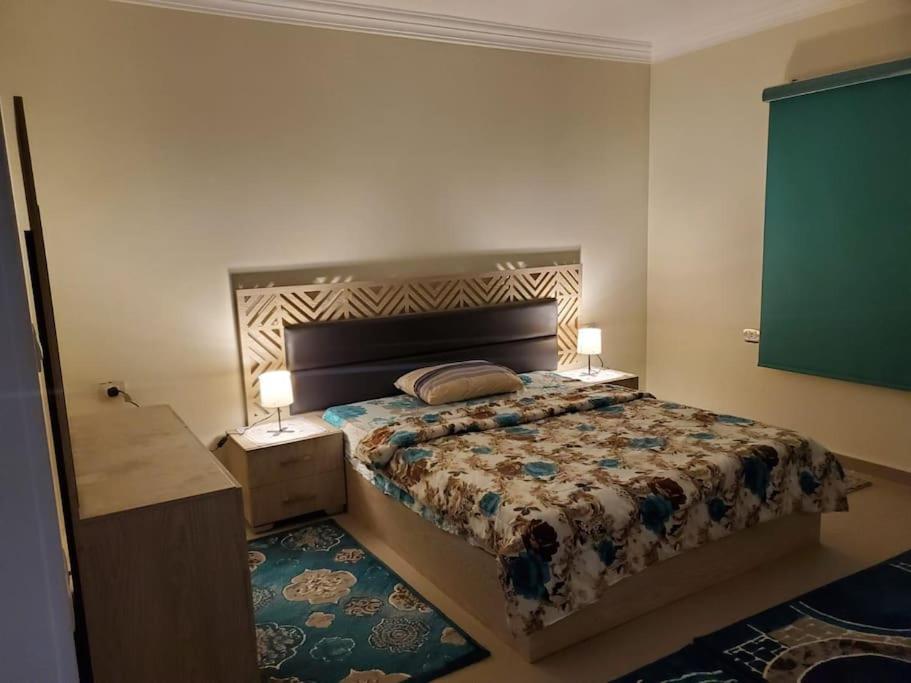 a bedroom with a bed with two lamps on it at Stylish 3 bedroom apartment close to the Pyramids and Grand Egyptian Museum in ‘Ezbet `Abd el-Ḥamîd