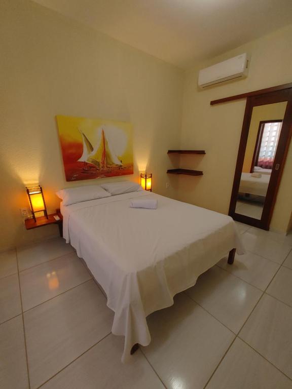 Pousada Viva Praia في باراكورو: غرفة نوم بسرير ابيض كبير ومصباحين