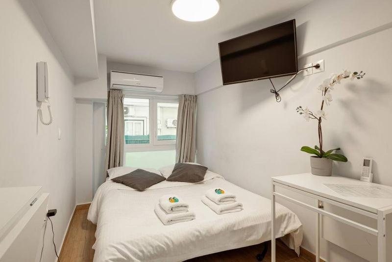 um quarto branco com uma cama com toalhas em Downtown Studio Thessaloniki em Tessalônica
