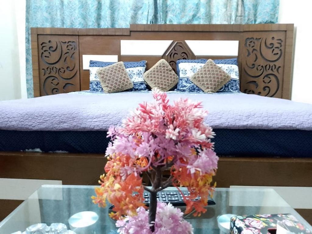 ハイデラバードにあるEmbassy inn Guest House Hyderabadのベッドルーム1室(ベッド1台、花の飾られたガラステーブル付)