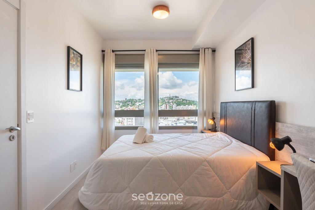 a bedroom with a large bed with a large window at AIR - Apartamentos bem localizados em Porto Alegre/RS in Porto Alegre
