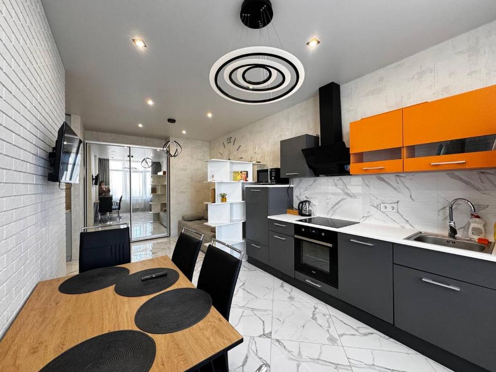 una cocina con mesa de madera y una cocina con armarios de color naranja en 45 Pearl Magnificent Apartment, en Odessa