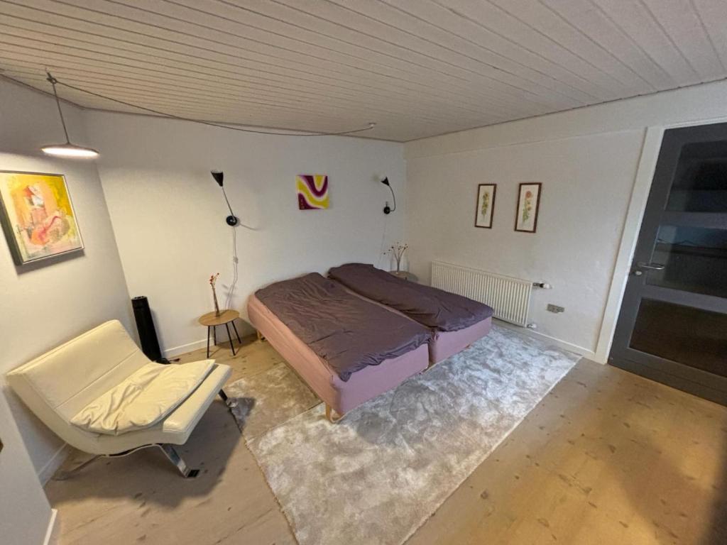 a bedroom with a bed and a chair at Vroldvej in Skanderborg