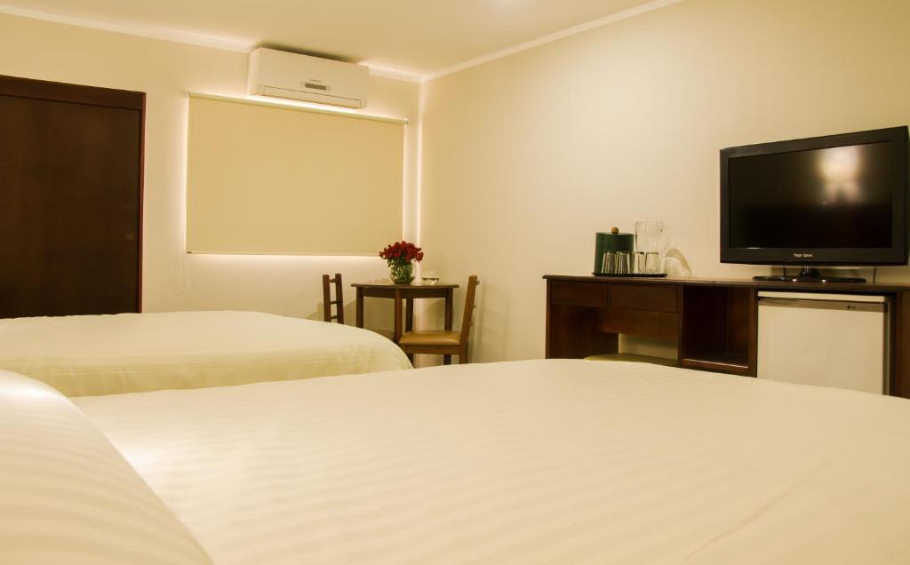 Una habitación de hotel con dos camas y un televisor de pantalla plana. en Hotel La Pedregosa, en Mérida
