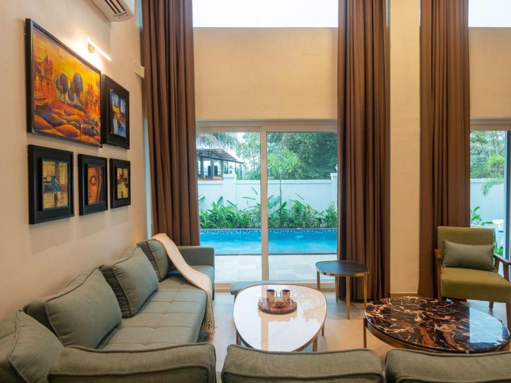 a living room with a couch and a table at Jade 4BHK Private Pool Villa by Le Pension Stays in Old Goa