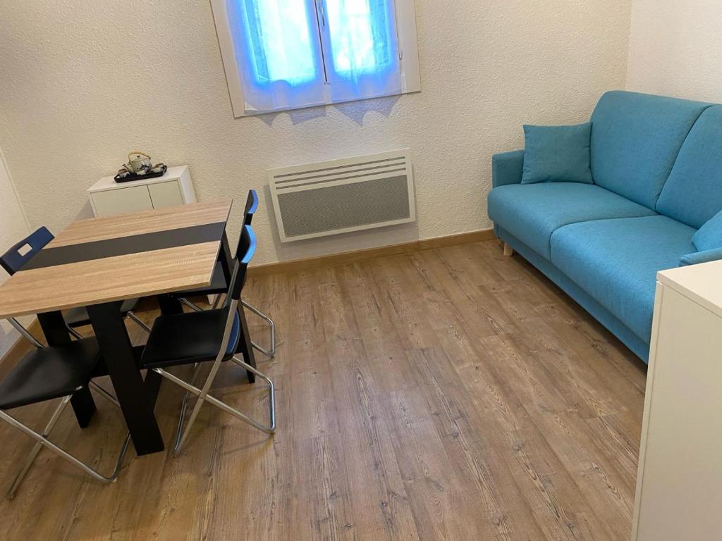 een woonkamer met een blauwe bank en een tafel bij Appartement au pied des pistes in Allos