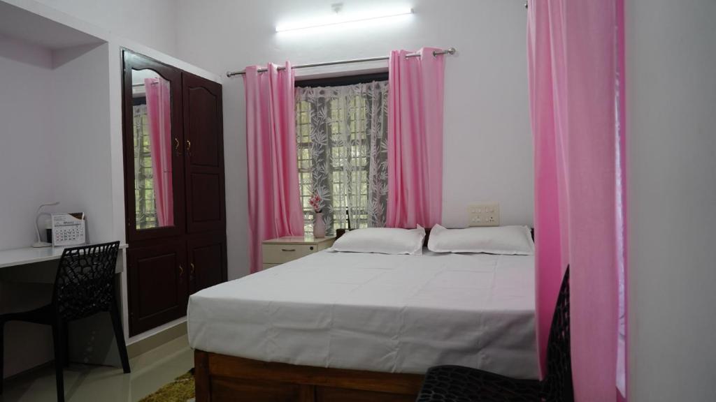 a bedroom with a large bed with pink curtains at Honey Paradise Homestay in Trivandrum