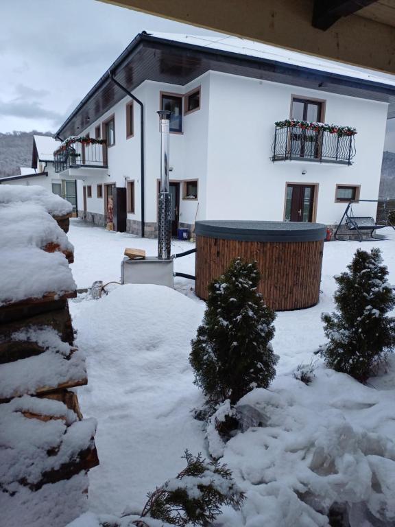 a snow covered yard with a house in the background at Casa Ovidiu Rasnov in Râşnov