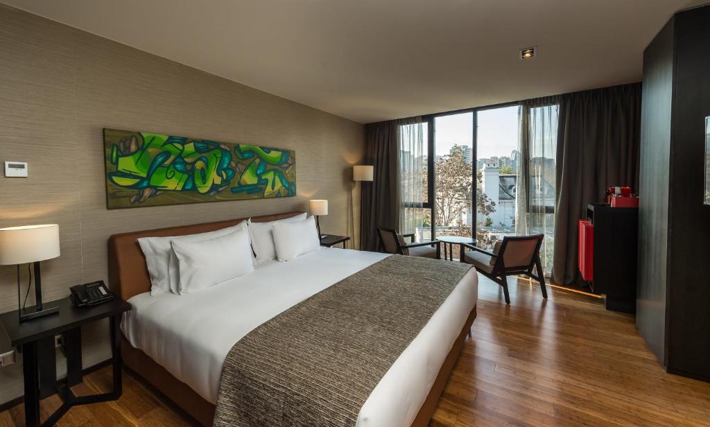 um quarto de hotel com uma cama e uma grande janela em Ladera Boutique Hotel em Santiago