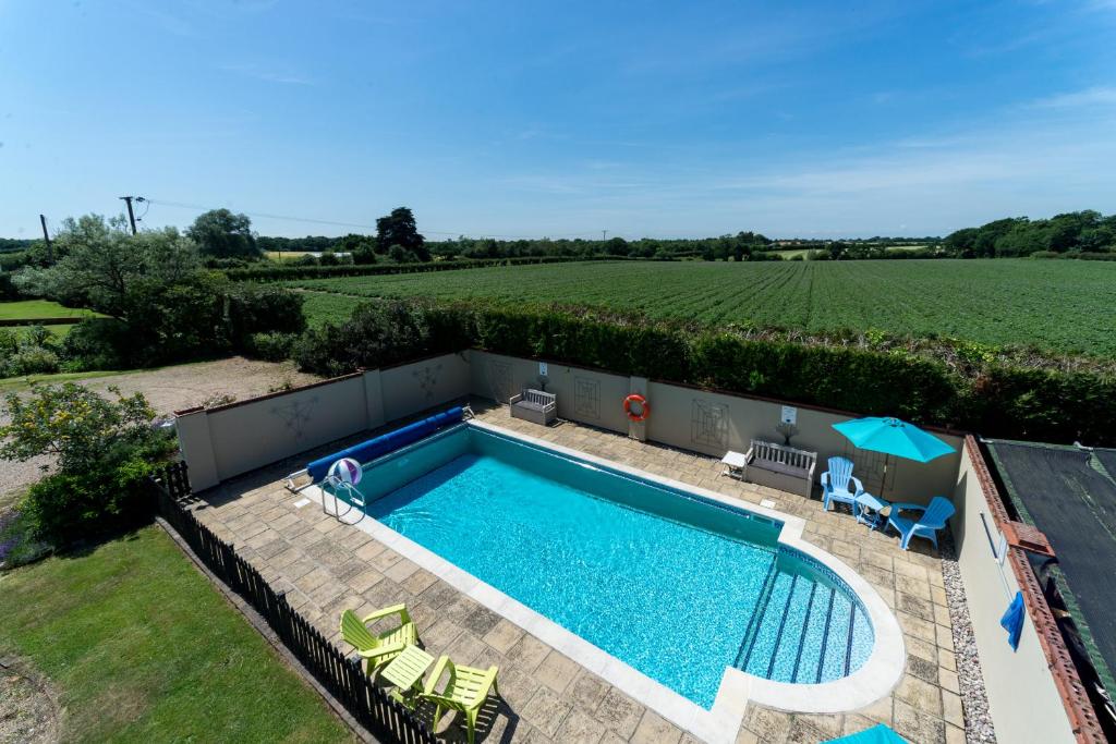 a swimming pool in the middle of a yard with a field at Birds Farm in Colchester